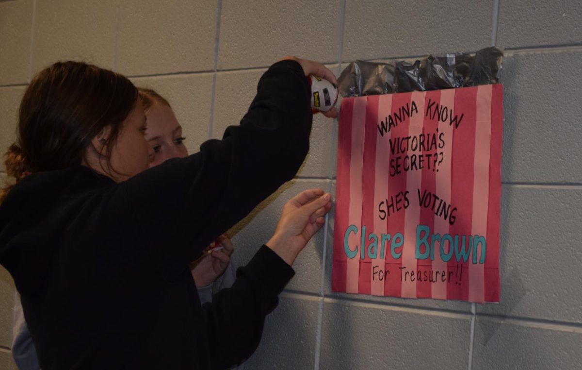 Kyla Arn (8) helps Clare Brown (8) put up her poster in the hallway. Clare ran for StuCo the secretary position.